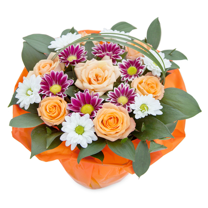 Presented against a pristine white background, this lush, freshly arranged bouquet channels the beauty and vitality unique to Weybridge. The overhead composition reveals a harmonious blend: at its centre, roses bloom in delicious gradients from soft peach to golden orange, their petals gently layered to invite a closer look. Nestled among these are clusters of chrysanthemums-some with icy white, daisy-like petals and zesty green centers that call to mind the wildflowers bordering the Thames Path; others stand out in deep magenta and purple shades, each vibrant petal culminating in a lively lime-green disc. Dense, dark ruscus leaves and other glossy greens border the bouquet, creating a rich, verdant foundation and highlighting the vivacious hues above. A slender ribbon of green decorative grass is woven into the design, arching lightly across the top and lending an element of grace reminiscent of the local gardens near Monument Hill. The bouquet's base is thoughtfully gathered in spirited crinkled orange paper, mirroring the sunny roses and infusing the arrangement with energy and warmth-much like the friendly bustle of Weybridge's high street on market day. Every aspect, from the interplay of soft and bold colours to the meticulous craftsmanship, speaks to a bouquet ready to brighten a local home, celebrate milestones, or simply infuse everyday life with a touch of nature's artistry in Weybridge.