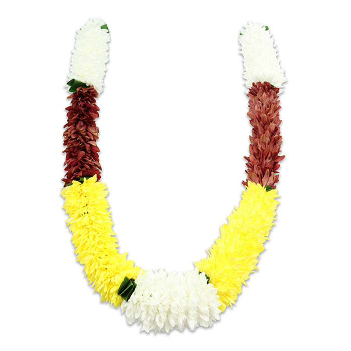 A meticulously crafted U-shaped ceremonial garland sits against a pure white field, the soft shadow beneath giving the impression of a delicate lift off the surface. The piece is composed of tightly packed synthetic petals shaped to resemble small chrysanthemums and marigolds; the arrangement reads as both highly finished and invitingly soft. Beginning at each top tip, a dense, cylindrical cluster of creamy white flowers provides a calm, auspicious opening, followed immediately by a compact swathe of maroon or reddish-brown that lends a grounded, almost earthen depth. The central curve of the 'U' is dominated by a long, plush section of bright yellow-radiant and broad-which carries the eye down to the bottom meeting point, where a wide, lush cluster of white flowers forms a luminous focal knot. Small, dark green leaf accents are placed intermittently to mark the transitions, most noticeably between the yellow and the lower white cluster, adding definition and a hint of botanical realism to the otherwise fabric composition. The craftsmanship is apparent in the consistent petal density, the secure joining of segments, and the rich visual rhythm created by the repeating color blocks. In Weybridge this traditional mala would be familiar in domestic puja corners, at community temple offerings along Walton Road, and as an emblematic adornment in weddings and Diwali displays, where the palette-white signifying purity, yellow denoting prosperity, maroon expressing devotion-carries meaning as much as the tactile softness conveys care.