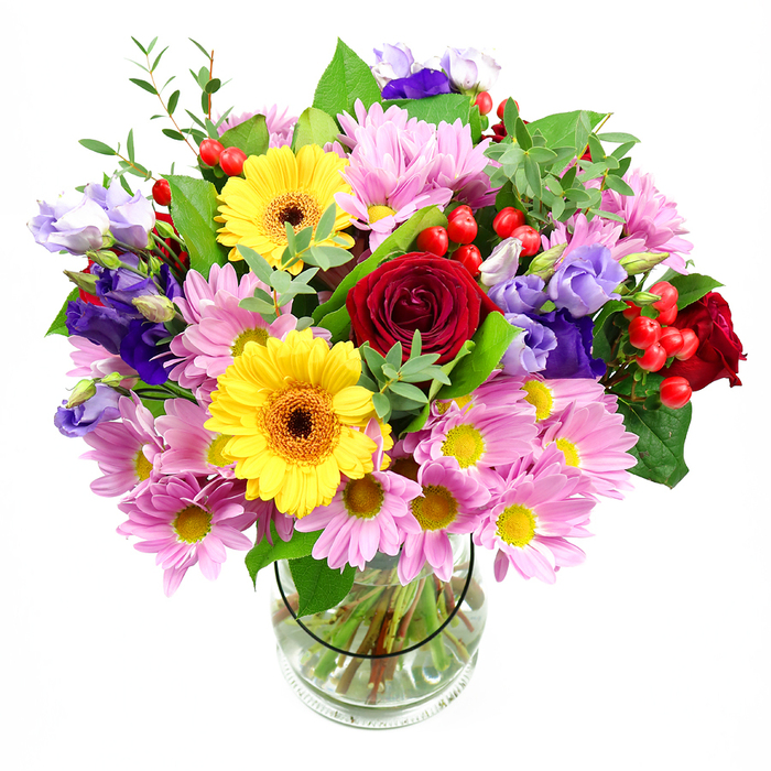 A lush, carefully shaped bouquet rises from a plain glass vase, photographed against a clean white backdrop that allows every flower and leaf to be clearly seen. At the centre, sumptuous deep red roses open in layered spirals, their velvet petals creating rich pools of colour that instantly suggest romance and warmth. Flanking them, bright yellow gerbera daisies with dark, warm-toned centres lean forward as if smiling, their bold, circular faces giving the design a friendly, celebratory feel. Surrounding these statement blooms is a generous halo of pink and soft lavender daisies or chrysanthemums, their many slender petals overlapping to form a cushion of texture and pastel colour. Intertwined throughout are stems of purple and lilac lisianthus, their soft, bell-shaped flowers and gently curled edges adding a refined, almost graceful movement to the arrangement. Here and there, clusters of round red hypericum berries peek out between petals, glossy and bright, like little jewels tucked into foliage for an unexpected touch of charm. The greenery is abundant and layered, with both deep green, broad leaves and finer, lighter sprigs that help create a natural, garden-like fullness, reminiscent of the greenery around Weybridge's Brooklands area in early summer. Through the transparent glass, neatly cut stems fan slightly as they meet in clear water, a subtle detail that reflects professional craftsmanship and freshness. The bouquet as a whole feels like an invitation to celebration-perfect for a birthday table in a Weybridge townhouse, a thank-you gift sent to an office near Monument Hill, or simply a radiant arrangement to bring colour and comfort into a quiet living room.